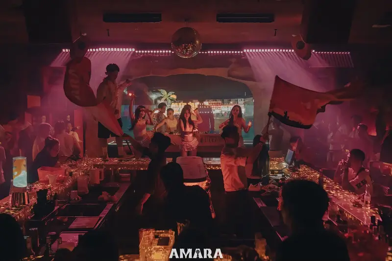 Bục DJ trong khung vòm sáng và quầy bar giữa phòng AMARA